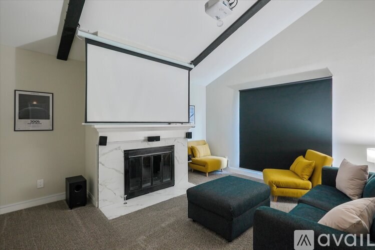A living room with a fireplace, a white screen, and a yellow chair.