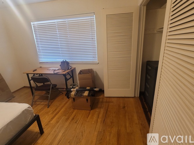 A room with wooden floors, a bed, a desk, and a chair.