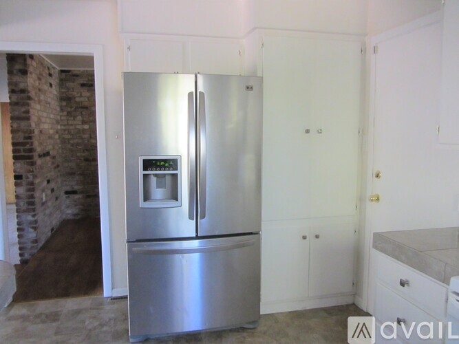 A stainless steel refrigerator with a digital display is in a kitchen with white cabinets.
