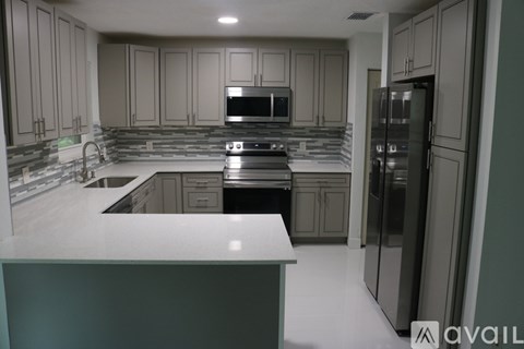 A kitchen with a white countertop and a refrigerator on the right.