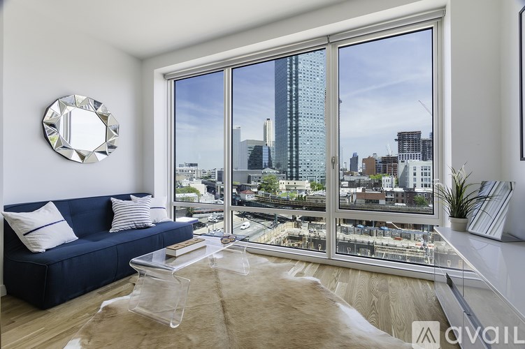 A living room with a blue couch and a large window overlooking a cityscape.