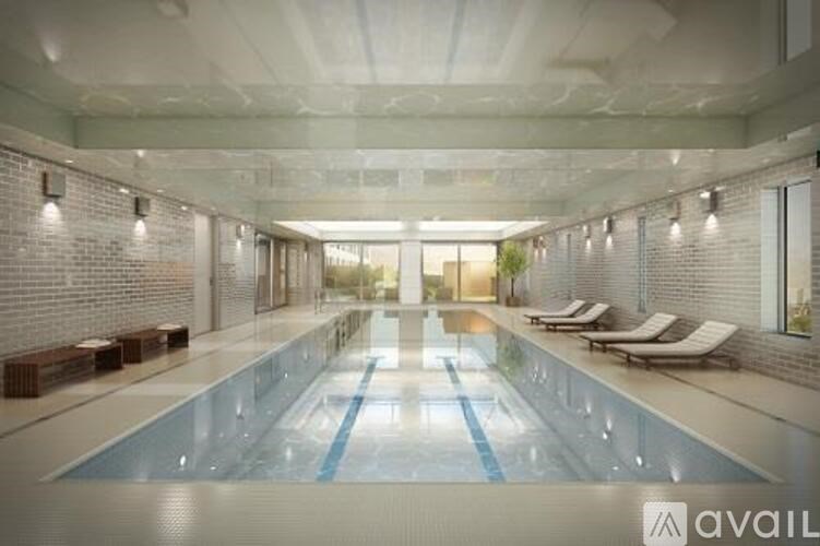 A large indoor swimming pool with lounge chairs on the side.