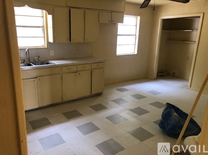 A kitchen with white cabinets and a checkered floor.