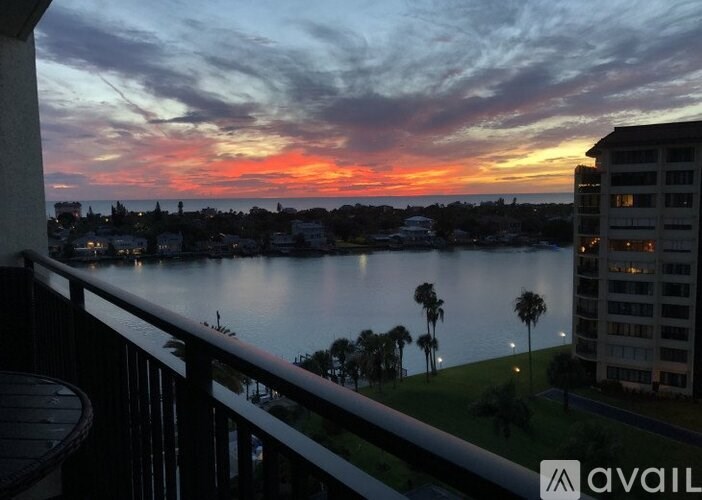 A sunset view from a balcony overlooking a lake and buildings.