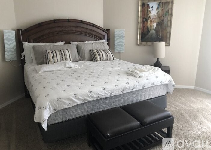A bed with a white comforter and a brown headboard.