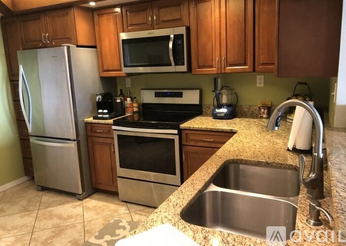 A kitchen with a refrigerator, oven, sink, and microwave.