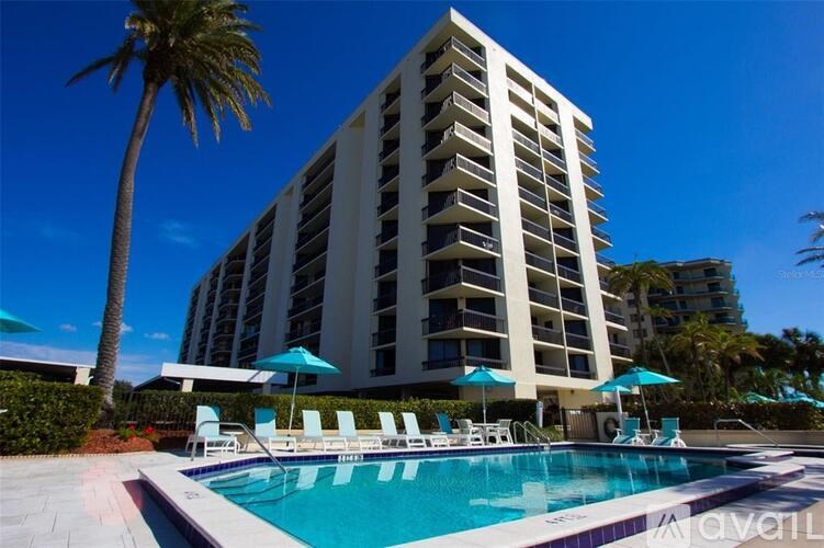 A tall white building with a pool in front of it.