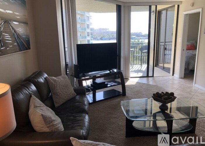 A living room with a black leather couch and a glass coffee table.
