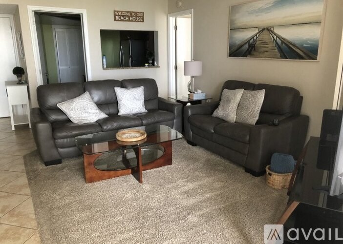 A living room with two black leather couches and a coffee table.