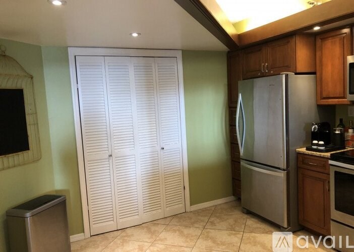 A kitchen with a refrigerator, a stove, and a set of white closet doors.