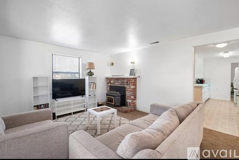 A living room with a grey couch and a fireplace.