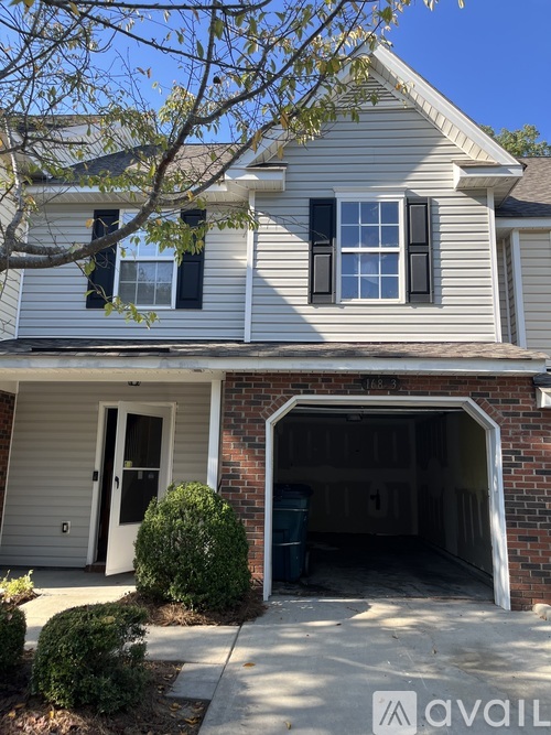 A house with a garage and a tree in front.