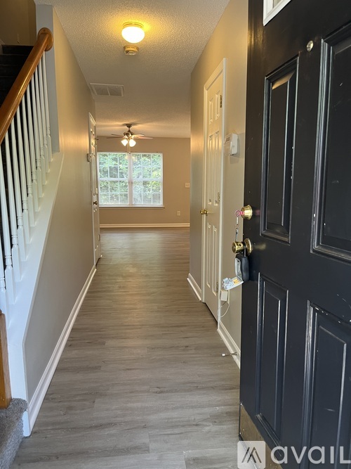 A hallway with a black door and a white door on the other side.