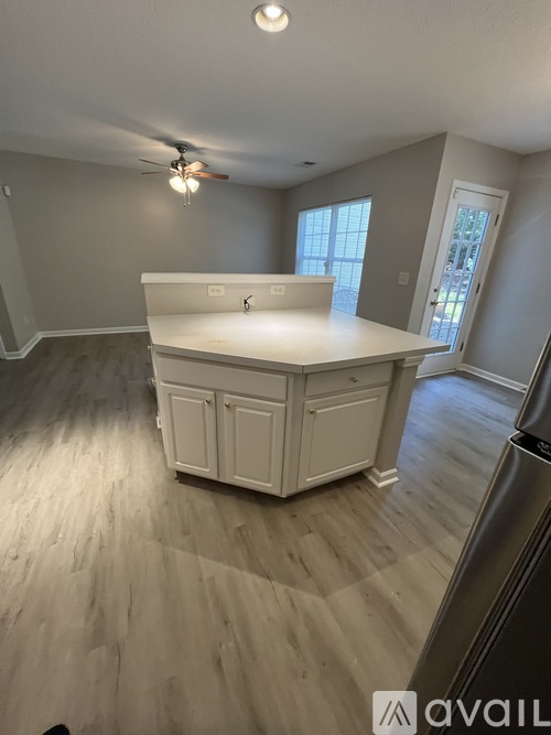 A kitchen with a white island and wooden floors.
