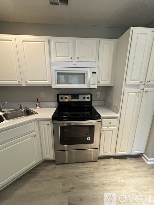 A kitchen with white cabinets and a stainless steel oven.