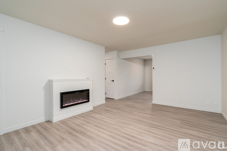 A spacious room with a fireplace and wooden flooring.