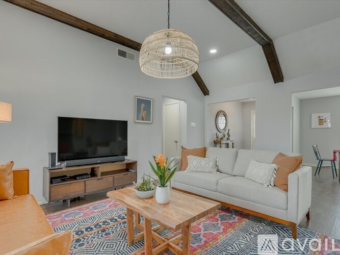 A living room with a white couch, a wooden coffee table, and a flat-screen TV.