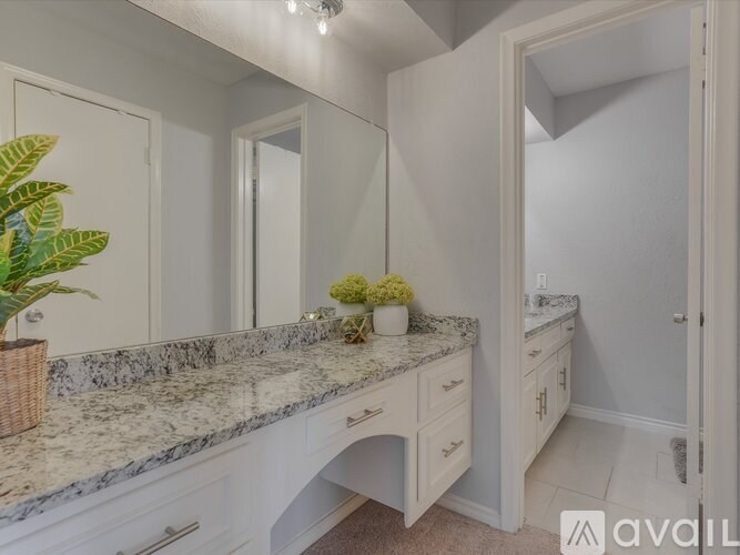 A bathroom with a marble countertop and white cabinets.