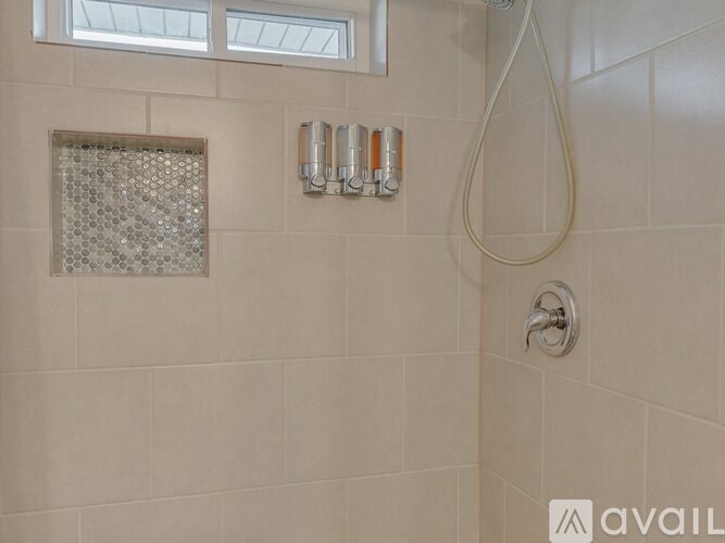 A shower area with a glass block window and a shower head.