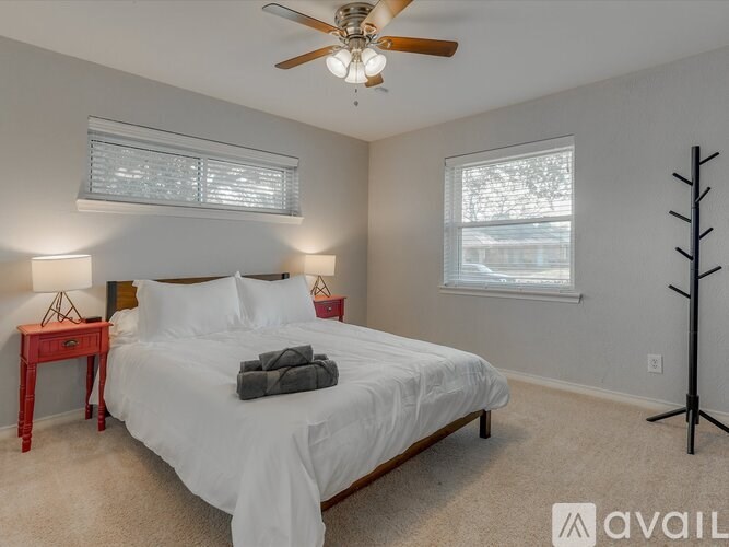 A bedroom with a bed, a ceiling fan, and two lamps.