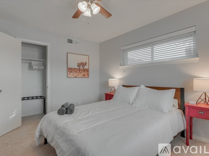 A bedroom with a bed, a ceiling fan, and a painting on the wall.