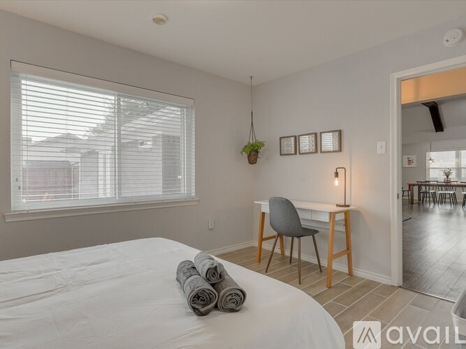 A bedroom with a large bed and a desk with a chair.