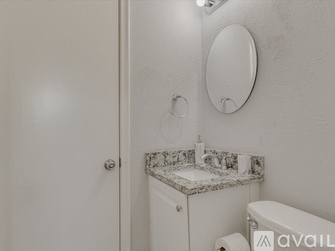 A bathroom with a sink, mirror, and toilet paper holder.