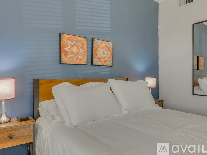 A bed with white pillows and a lamp on a nightstand.