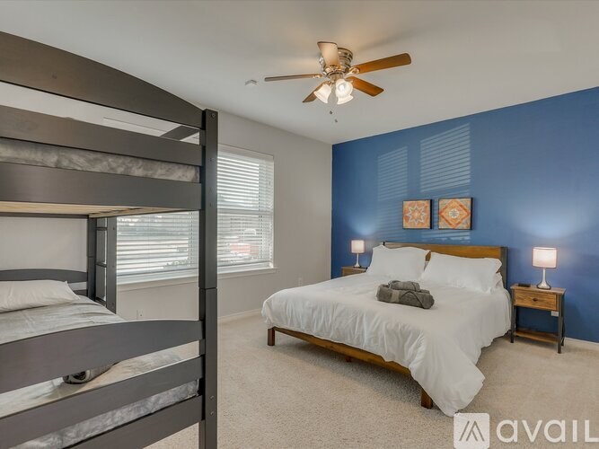 A bedroom with a bunk bed and a single bed with a ceiling fan.
