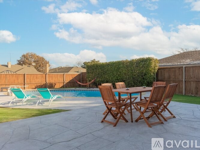 A backyard with a pool, chairs, and a table.