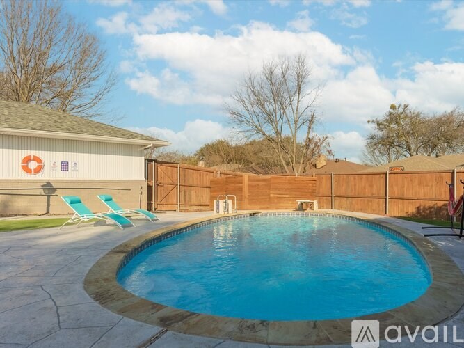 A pool with a blue water and chairs around it.