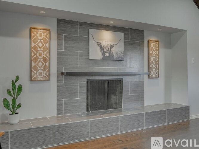 A modern living room with a grey tiled fireplace and a painting of a bull above it.