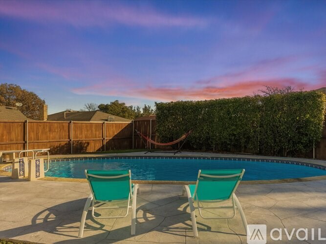 Two green chairs are placed on a patio in front of a pool.