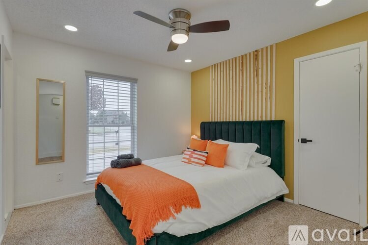 A bedroom with a bed, pillows, and a ceiling fan.