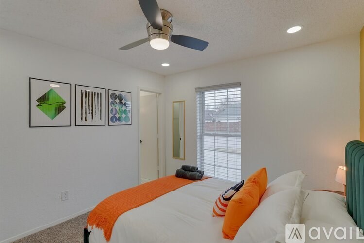 A bedroom with a bed, a ceiling fan, and a window.