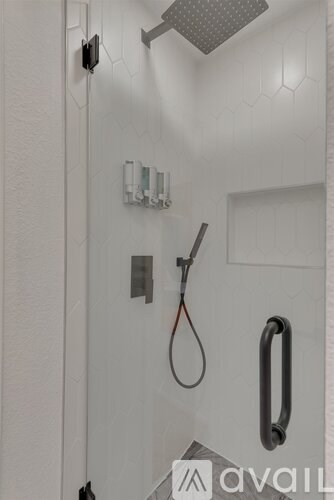 A white shower stall with a hose and a shower head.