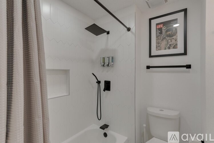 A bathroom with a white toilet and a white bathtub with a shower head.
