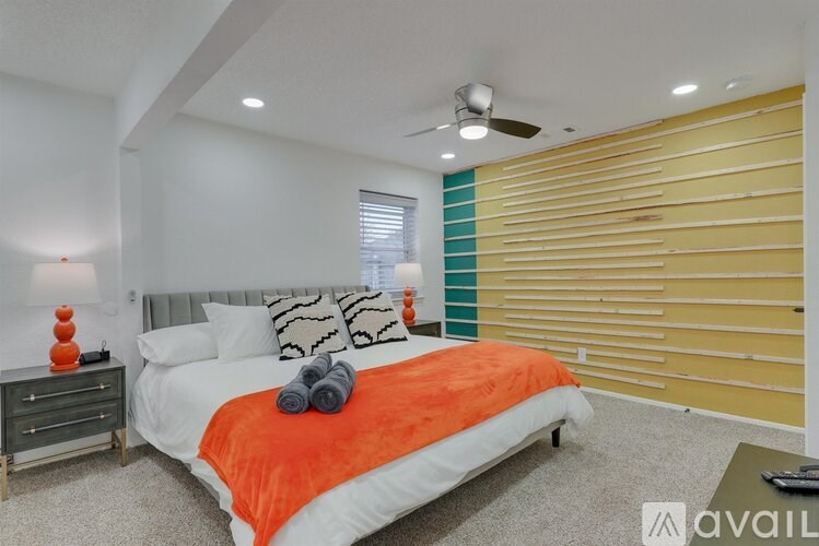 A bedroom with a bed, pillows, and a ceiling fan.