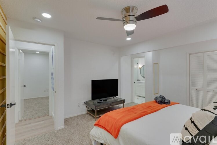 A bedroom with a bed, a television, and a ceiling fan.