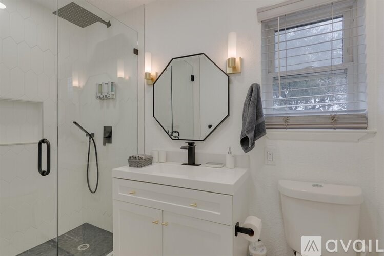A bathroom with a white vanity, a mirror, and a shower.