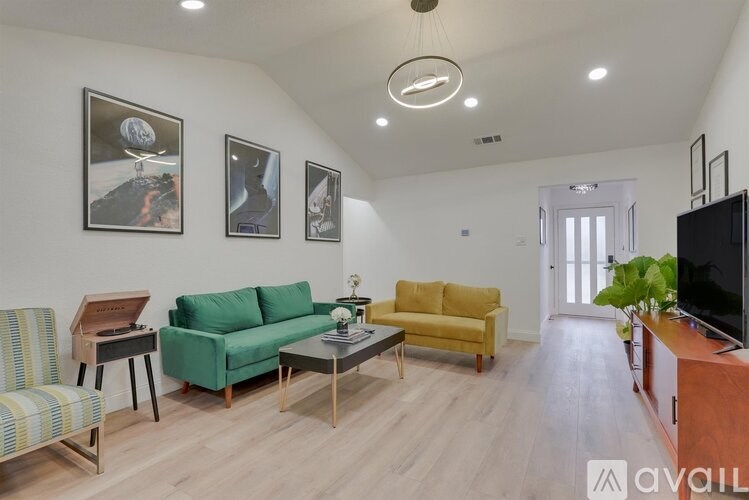 A living room with a green couch, yellow couch, and a television.