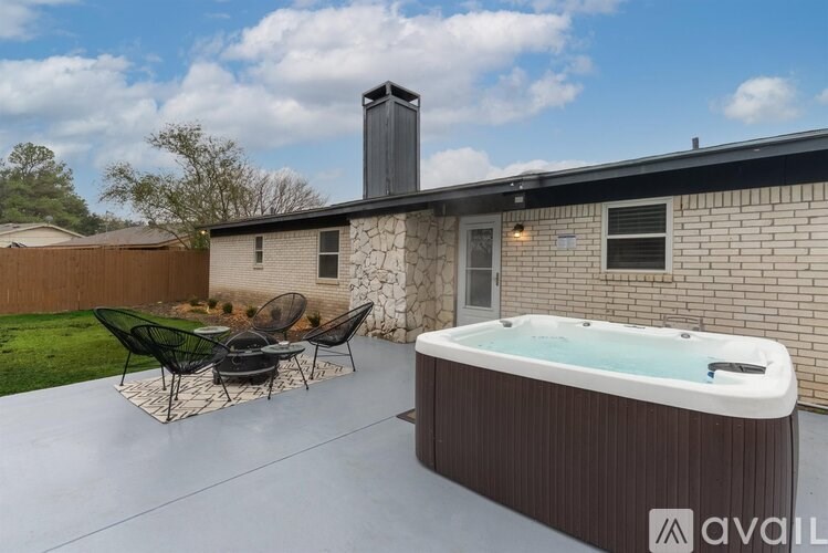 A hot tub is on a patio in front of a house.