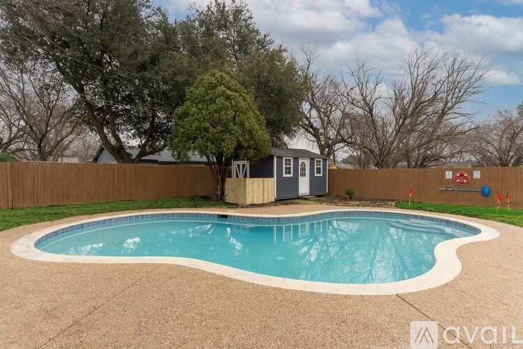 A small pool with a concrete border and a small building next to it.