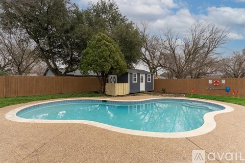 A small pool with a concrete border and a small building next to it.