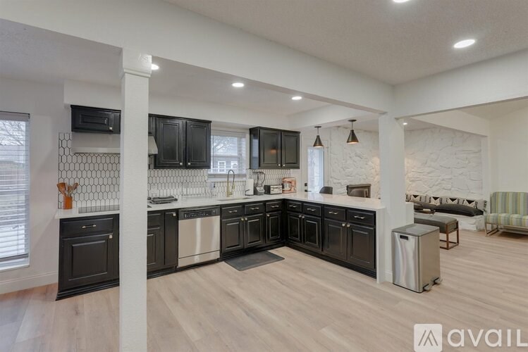 A modern kitchen with black cabinets and a wooden floor.