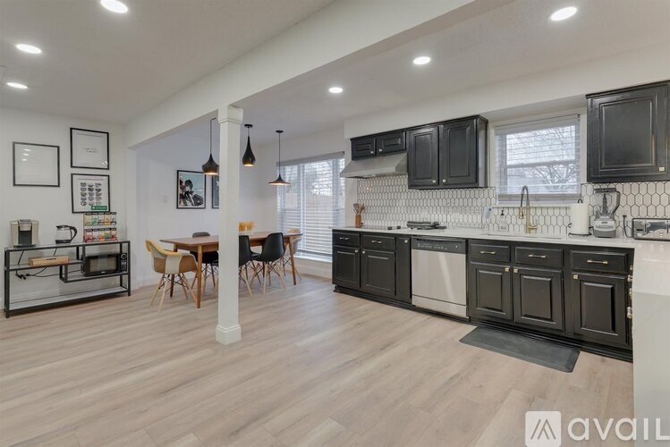 A kitchen with black cabinets and a wooden floor.