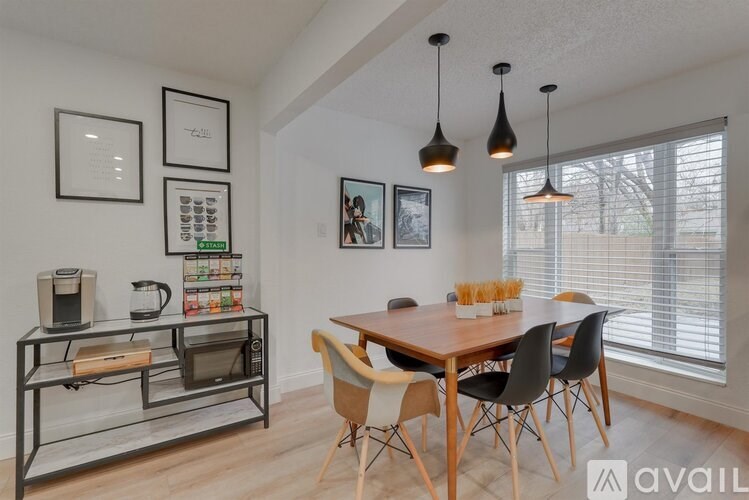 A kitchen with a table and chairs and a microwave on a cart.