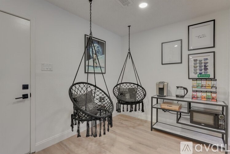 Two hanging chairs in a room with a microwave and other appliances on a counter.