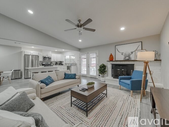 A living room with a white couch, a blue armchair, a coffee table, and a fireplace.