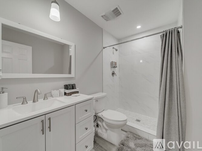 A bathroom with a white toilet, sink, and shower area.